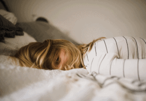 Woman lying awake in bed by Kinga Cichewicz