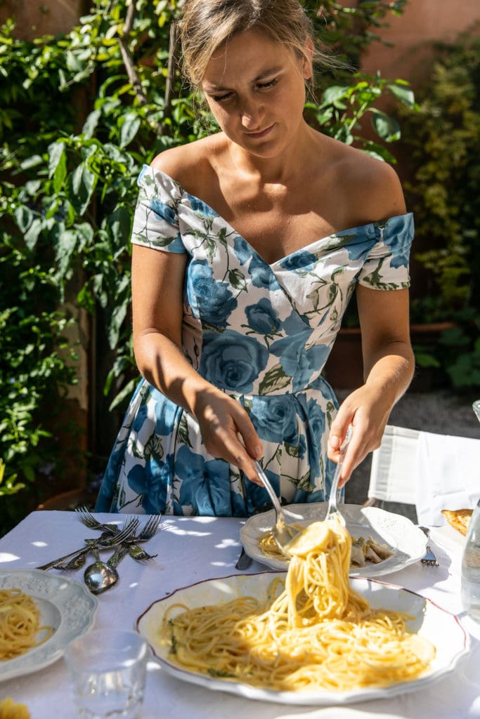 Skye McAlpine wears a blue and white floral dress while serving pasta for an alfresco meal