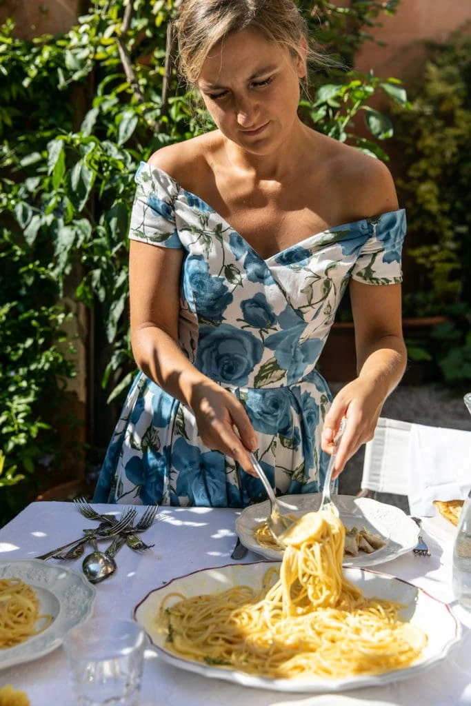 Skye Mcalpine Wears A Blue And White Floral Dress While Serving Pasta For An Alfresco Meal