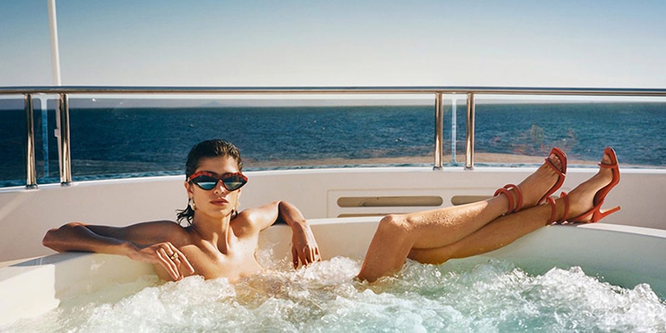 A model lounges in a Jacuzzi wearing Bottega Veneta shoes and sunglasses; the Italian brand has launched their playlists online during lockdown